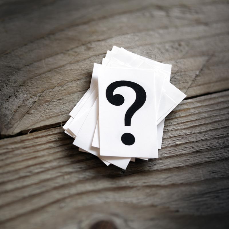 Index cards stacked on wood background. Top card features a large question mark