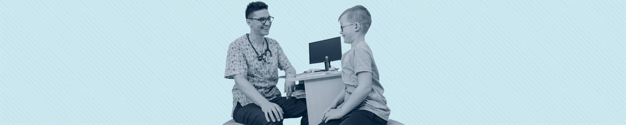 A nurse examines a smiling young boy in glasses.